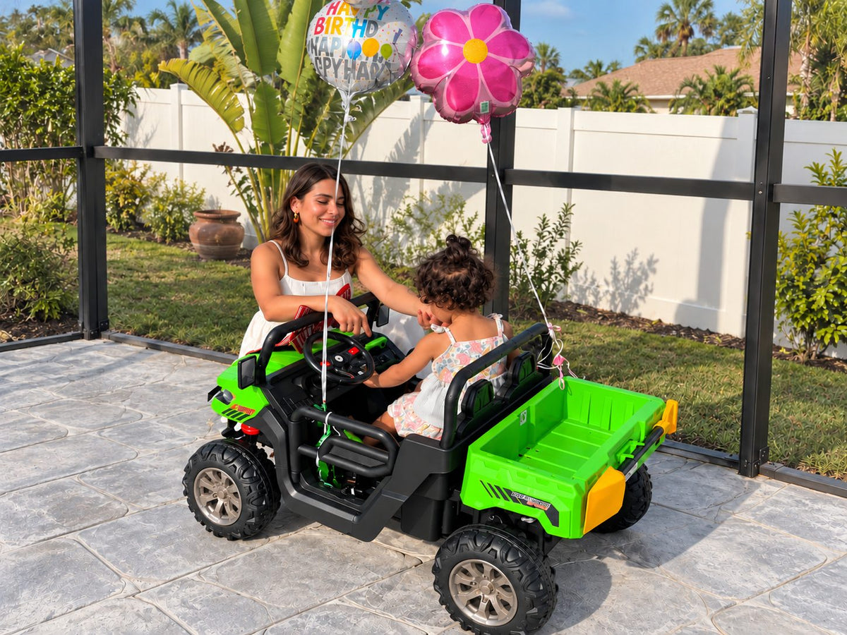 A mom leans in to help her daughter in a green ride-on UTV decorated with birthday balloons
