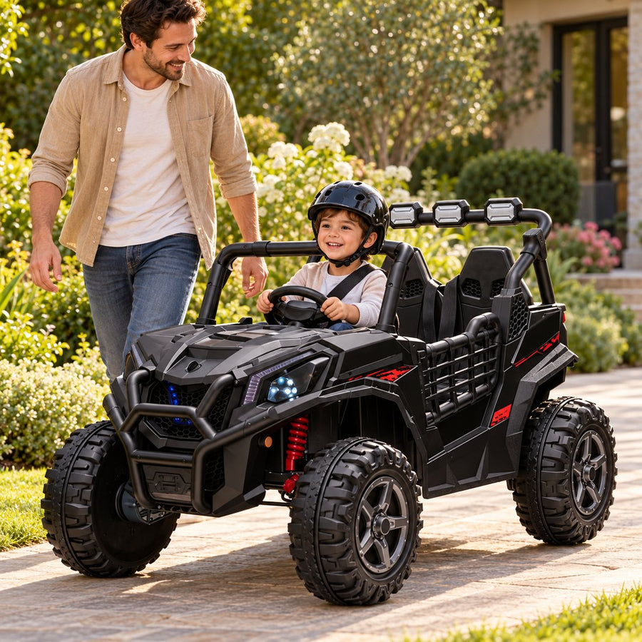 A parent walks beside a child in a helmet driving the black UTV along a garden path